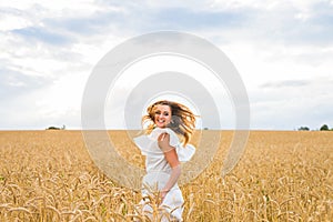 Happy woman jumping in golden wheat