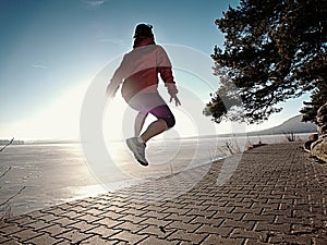 Happy woman jumping on lake shore, path beach at sunset