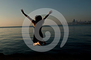 Happy woman jumping near by Lake Michigan at sunrise