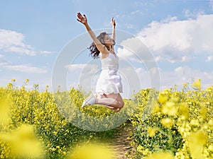 Happy woman jumping with raised hands outdoor.