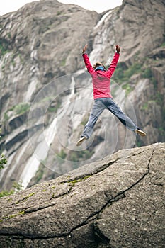 Happy woman jumping on rock in mountains