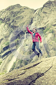 Happy woman jumping on rock in mountains