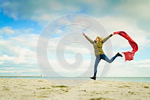 Happy woman jumping with scarf on beach