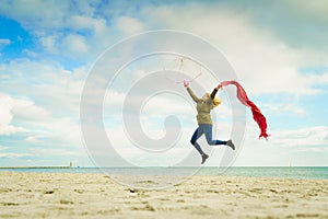 Happy woman jumping with scarf on beach