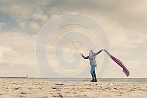 Happy woman jumping with scarf on beach