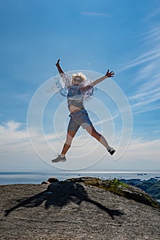 Happy woman is jumping on the top of the mountain. He rejoices at the success of victory over himself, overcoming