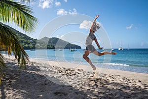 Happy woman jumping up on the beach to celebrates summer holidays