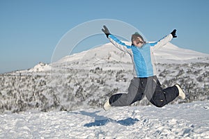 Happy woman jumping at winter mountains, active female enjoying nature,