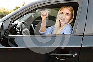 Happy woman with keys in car, driving school