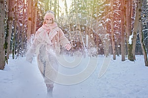 A happy woman kicks the snow, a winter forest with frozen trees