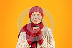 Happy Woman In Knitwear Enjoying Coffee Holding Mug, Yellow Background