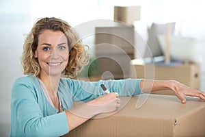 happy woman labeling moving box at home