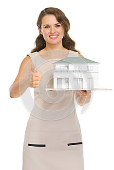 Happy woman landlord with scale model of house