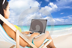 Happy woman with laptop on the beach