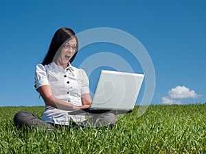 Happy woman with laptop on a meadow