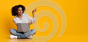 Happy Woman With Laptop Pointing At Copy Space Over Yellow Background