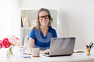 Happy woman with laptop working at home or office