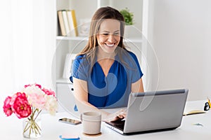 Happy woman with laptop working at home or office