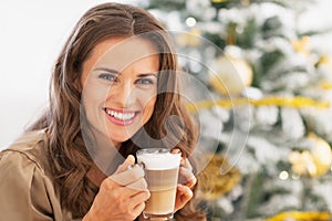 Happy woman with latte macchiato in front of christmas tree