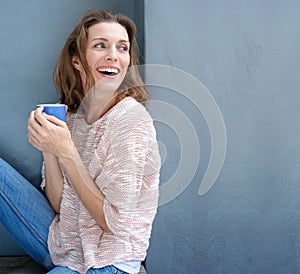 Happy woman laughing with a cup of coffee in hand