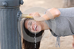 Happy woman laughing drinking water from public fountain