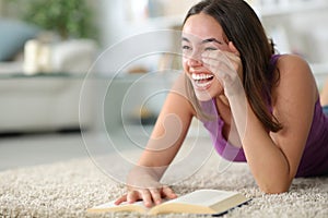 Happy woman laughing hilariously reading a comedy paper book photo