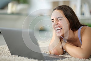 Happy woman laughing loudly watching media on laptop