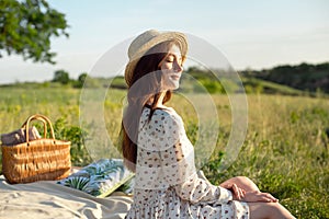Happy Woman Life Style, beautiful relaxed girl in a straw hat on the nature picnic basket flowers in the rays of the