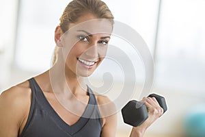 Happy Woman Lifting Weights At Health Club