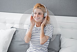 Happy woman listening to music relaxing on bed, music. Resting woman enjoying music