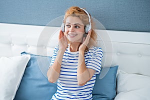 Happy woman listening to music relaxing on bed, music. Resting woman enjoying music