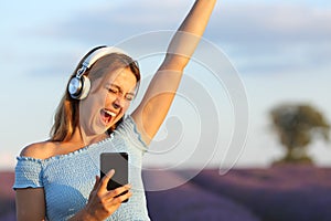 Happy woman listening to music and singing in lavender field