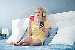 Happy woman listening to music on smartphone at home, music
