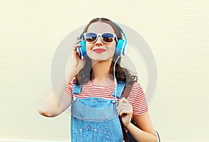 Happy woman listens to music in headphones over white