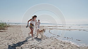 Happy woman and little boy running with dog on the sea coast