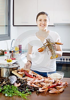 Happy woman with lobster in home kitchen