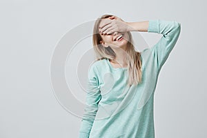 Happy woman with blonde hair closing eyes with hand going to see surprise prepared by boyfriend standing and smiling in