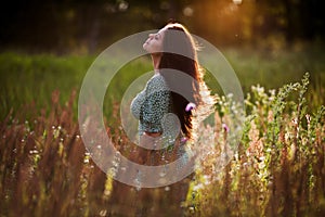 Happy woman with long hair in a field in the evening