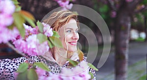 Happy woman looking away in park during cherry tree blooming photo