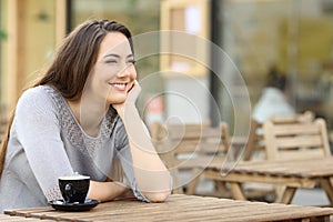 Happy woman looking away sitting on a coffee shop