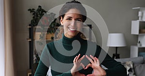 Happy woman looking at camera joining fingers showing heart shape