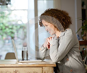 Happy woman looking at computer at home