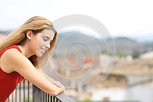 Happy woman looking down in a balcony in a town