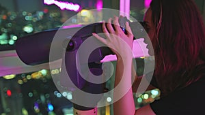 Happy woman looking night cityscape in telescope