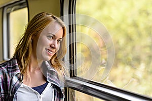 Happy woman looking out train window pensive