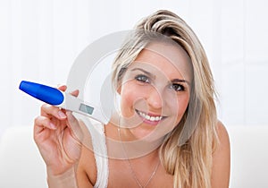 Happy woman looking at positive pregnancy test