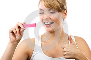 Happy woman looking at pregnancy test with positive result and showing thumbs up