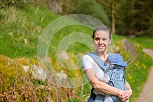 Happy woman looking an smiling to camera while holding her baby photo