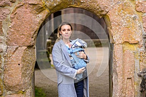 Happy woman looking to camera while holding and carrying her baby in a baby carrier photo