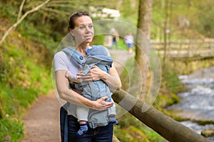 Happy woman looking to distance while holding and carrying it in a baby carrier photo